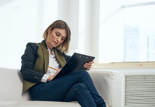 Business woman in suit with documents sitting on sofa indoors. High quality photo