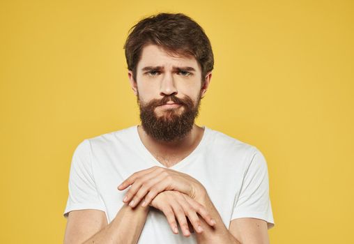 Emotional brunette man gestures with his hands on a yellow background. High quality photo