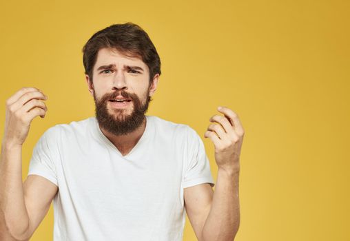 An energetic man on a yellow background gestures with his hands cropped view. High quality photo