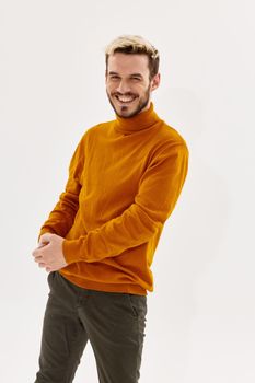 happy blond guy in an orange sweater and trousers laughs on a light background. High quality photo