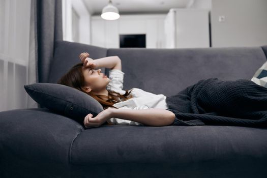 woman lying on the couch health problem hiding with a blanket. High quality photo