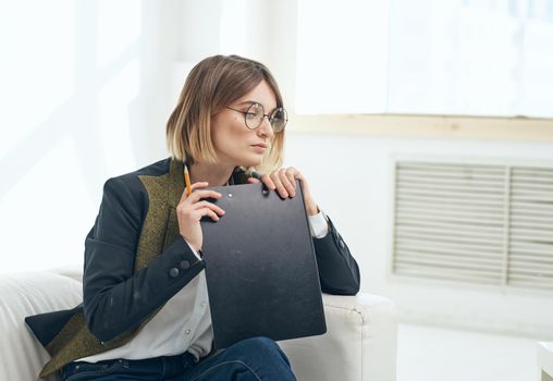Business woman with a folder of documents and in a classic suit indoors near the window. High quality photo
