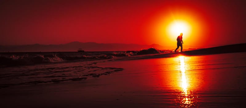 Silhouette of a man by the sea. Beautiful blazing sunset sea landscape. Amazing summer sunset view on the beach. 