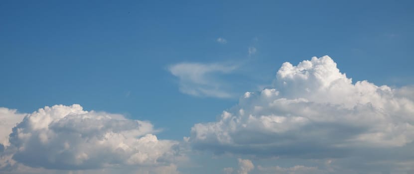 Nature background. White cumulus clouds on the blue sky