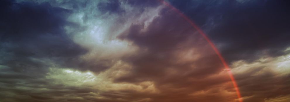 Rainbow in the sky against dark dramatic clouds 