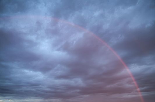Rainbow in the sky against dark dramatic clouds 