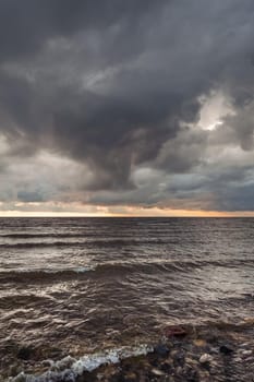 Amazing dramatic landscape. Dramatic dark clouds during sunset at sea. Dark sea water and heavy beautiful grey clouds.