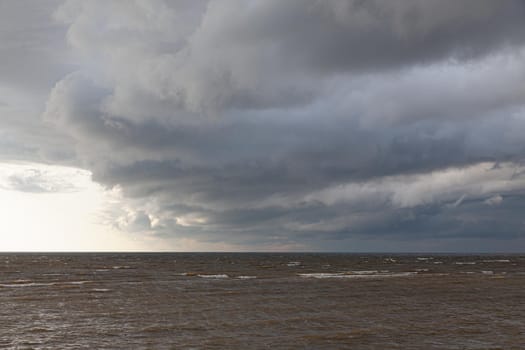 Amazing dramatic landscape. Dramatic dark clouds during sunset at sea. Dark sea water and heavy beautiful grey clouds.