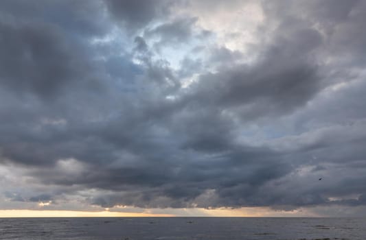 Amazing dramatic landscape. Dramatic dark clouds during sunset at sea. Dark sea water and heavy beautiful grey clouds.