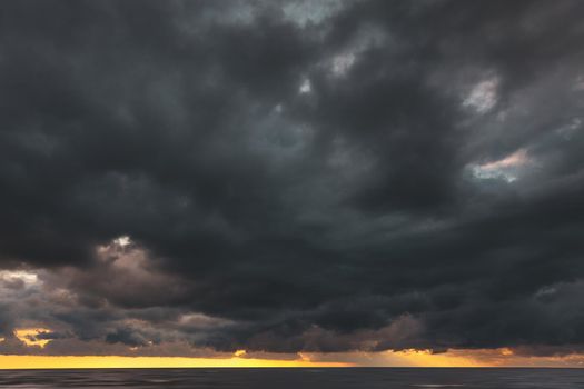Amazing dramatic landscape. Dramatic dark clouds during sunset at sea. Dark sea water and heavy beautiful grey clouds.