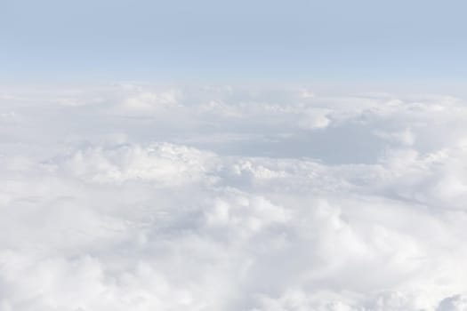 Sky with clouds, a view from an aeroplane above the clouds. Abstract nature background with clouds in light tonality. White cumulus clouds
