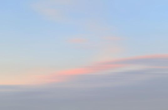 Blurry shot of the sunset sky. Abstract nature background with clouds in light tonality. 
