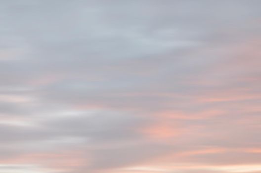 Blurry shot of the sunset sky. Abstract nature background with clouds in light tonality. 