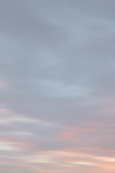 Blurry shot of the sunset sky. Abstract nature background with clouds in light tonality. 