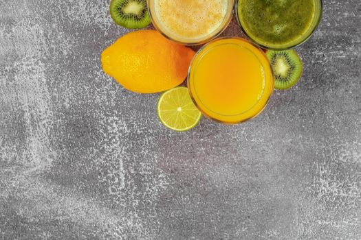 Top view of glasses of orange juice and banana kiwi and spinach smoothies with copy space.