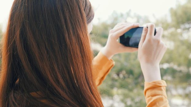 woman outdoors with a phone in her hands taking pictures of nature panorama rest. High quality photo