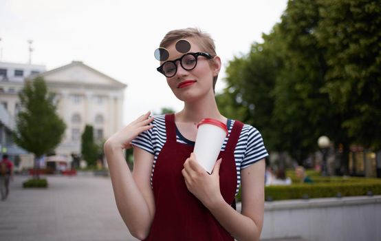 fashionable woman in a sundress and glasses on her face street nature summer trees building. High quality photo