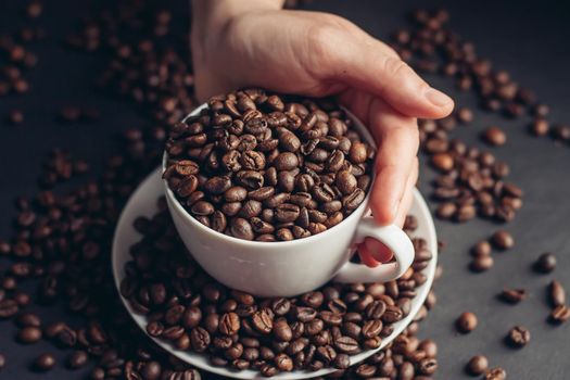 a cup with coffee beans stands on a saucer on a gray background close-up. High quality photo