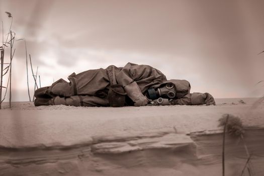 Apocalypse. A person dies after wearing a gas mask and a chemical protection suit. a polluted post atomic landscape. The concept of the radiation apocalypse after the atomic war. Loneliness.