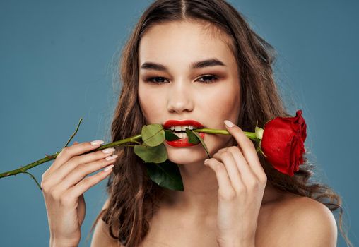 Woman with a rose in her teeth evening makeup blue background model. High quality photo