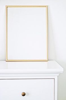 Golden frame for art, poster or photo in white interior, home decor concept