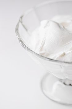 White whipped dessert cream served in a glass bowl, creamy texture closeup