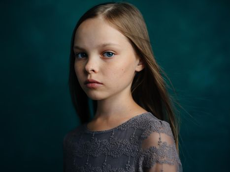 Portrait of a blue-eyed girl in a gray dress on a green background close-up beautiful face. High quality photo