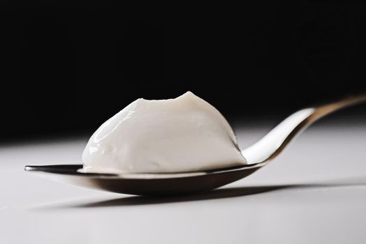 Thick white cream on golden spoon, closeup