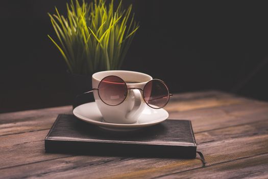 potted flower notepads pens stationery and coffee cup glasses wooden table. High quality photo