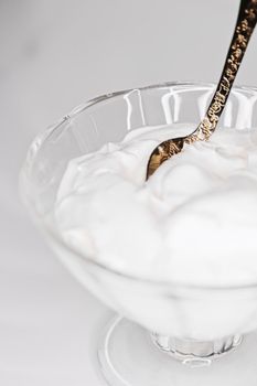 White whipped dessert cream served in a glass bowl, creamy texture closeup