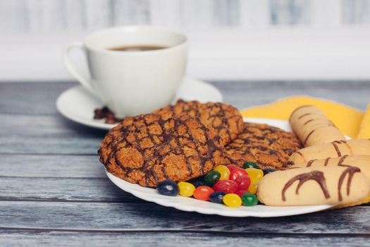 cookies on a plate a cup of tea on a wooden table a snack. High quality photo