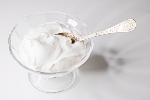 White whipped dessert cream served in a glass bowl, creamy texture closeup