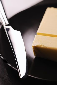 Sliced organic butter block and knife, breakfast food closeup