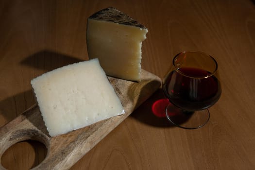 Cheese wedges on wooden board and red wine