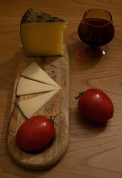 Cheese wedge with tomato, bread sticks and red wine