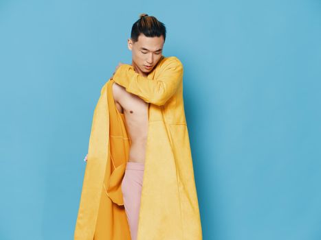 Semi-nude Asian man in yellow coat on blue background hairstyle model. High quality photo