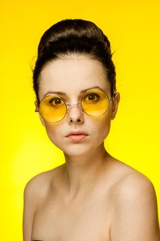 brunette with bare shoulders yellow glasses clear skin model. High quality photo