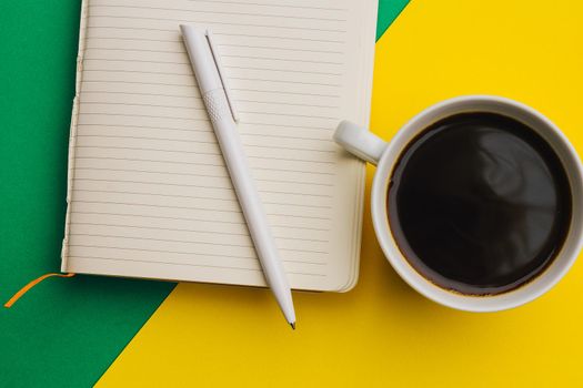 coffee cup on colored background and notepad pen top view office. High quality photo