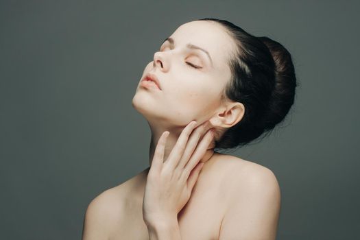 pretty brunette with bare shoulders gathered hair hand near face. High quality photo