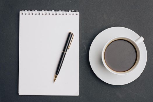 the dark background a Cup of coffee office Notepad handle the view from the top. High quality photo