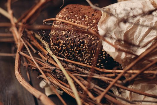 Loaf of Bread In a paper package lies on branches in a nest on a wooden table. High quality photo