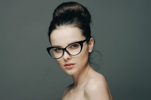 cute brunette with glasses naked shoulders gathered hair fashion. High quality photo