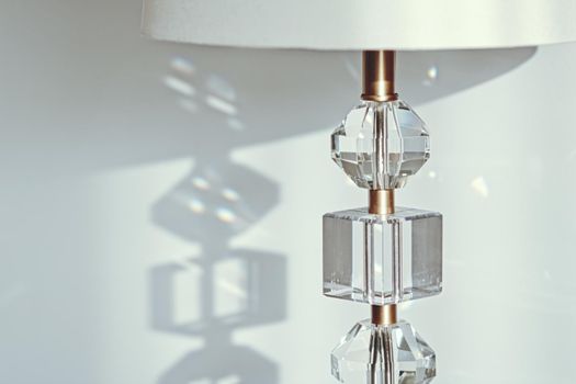 Gold and crystal details of a bedside lamp with shadows at sunset, luxury home decor closeup