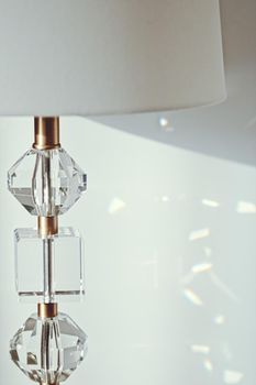 Gold and crystal details of a bedside lamp with shadows at sunset, luxury home decor closeup