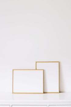 Two golden vertical and horizontal frames on white furniture, luxury home decor and design for mockup creations