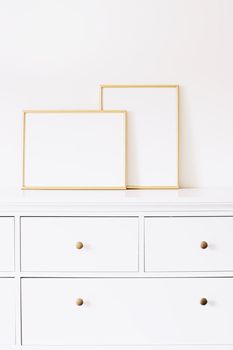 Two golden vertical and horizontal frames on white furniture, luxury home decor and design for mockup creations