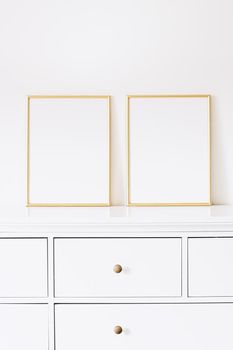 Two golden vertical frames on white furniture, luxury home decor and design for mockup creations