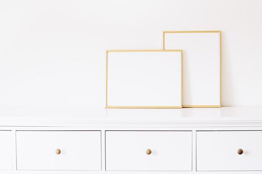 Two golden vertical and horizontal frames on white furniture, luxury home decor and design for mockup creations