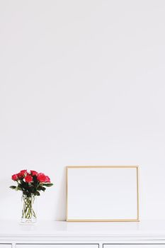 Golden horizontal frame and bouquet of rose flowers on white furniture, luxury home decor and design for mockup creations