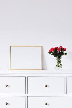 Golden horizontal frame and bouquet of rose flowers on white furniture, luxury home decor and design for mockup creations